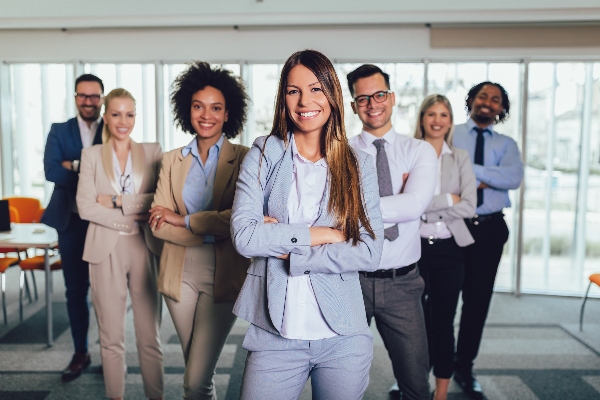 A group of business professionals stand smiling and ready to work on hiring new employees.