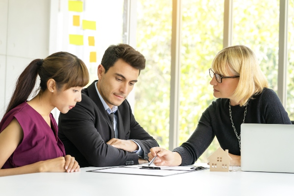 A recruitment specialist helps two job seekers understand a document.